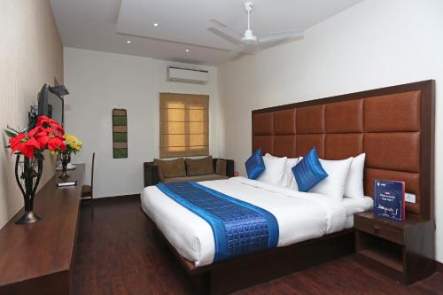 a hotel room with a large bed with blue pillows at OYO Asian Hospitality Near Aravali Biodiversity Park in Gurgaon