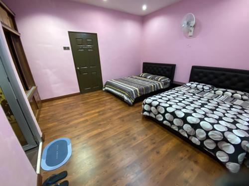 Duas camas num quarto com paredes cor-de-rosa e pisos em madeira em Frosty Hills Homestay em Tanah Rata