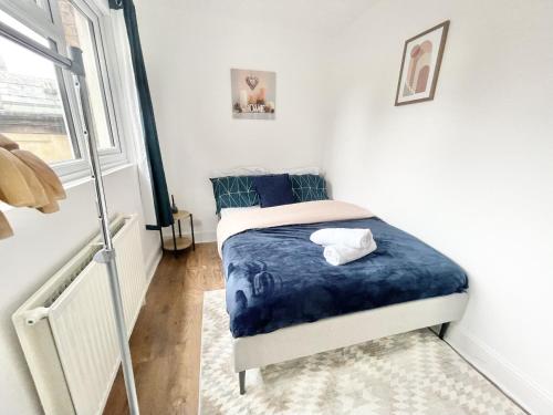 1 dormitorio pequeño con 1 cama con sábanas azules en MUST VIEW - Slick Retreat in Holloway - Next to Emirates Stadium - Sleeps up to 6 en Londres