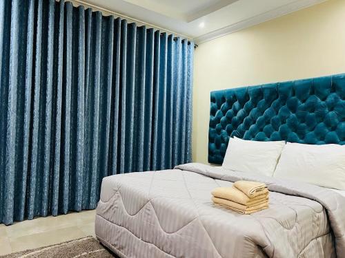 - une chambre avec un grand lit et des rideaux bleus dans l'établissement Roma Apartments, à Lusaka