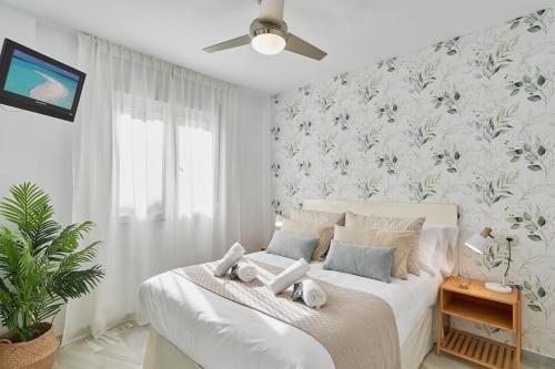 um quarto com uma cama branca e um papel de parede florido em Erisa I apartament La Carihuela 100 mts beach em Torremolinos
