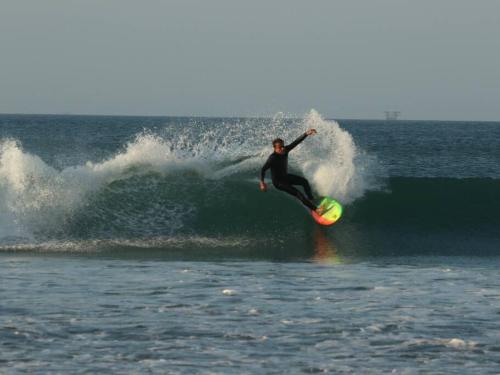 un homme chevauchant une vague sur une planche de surf dans l'océan dans l'établissement Casa del Norte: Casa del Norte: Mediterranean Charm in Lobitos, Peru - Ideal Surf Haven for All Levels, à Lobitos