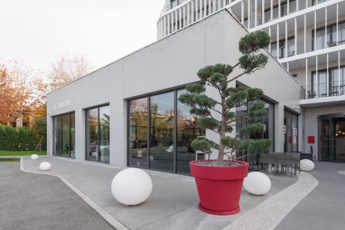 a large red pot with a tree in front of a building at KYRIAD LYON OUEST Limonest in Limonest
