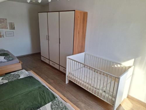 a bedroom with a crib and a white cabinet at Ferienwohnung Koller in Lam