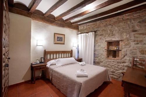 a bedroom with a bed and a stone wall at Hotel Convento San Roque in Balmaseda