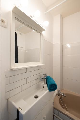 une salle de bain blanche avec un lavabo et un miroir dans l'établissement Le Rubis - Zenith, à Toulouse