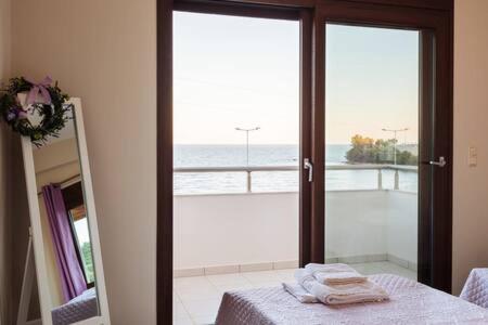 una camera da letto con balcone affacciato sull'oceano di Villa Armonia - Beachfront Majestic Retreat a Petalidi