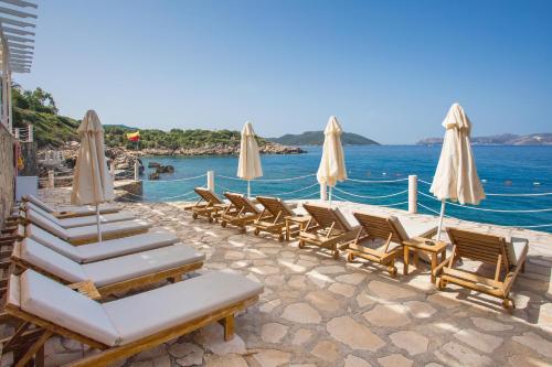 a group of lounge chairs and umbrellas on a beach at Aqua Princess Hotel in Kaş