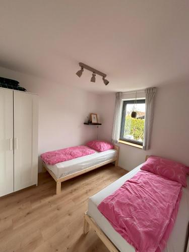 2 Betten in einem weißen Zimmer mit rosa Bettwäsche in der Unterkunft Albnest in Mössingen