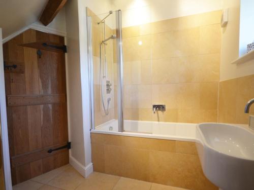 a bathroom with a shower and a tub and a sink at 1 Bed in Bibury 29026 in Quenington