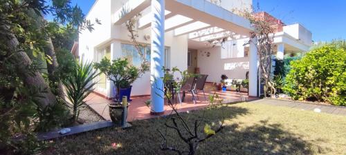 une maison blanche avec une terrasse couverte et une cour dans l'établissement Tabarca Chalet con jardín y piscina comunitaria, à Peñíscola