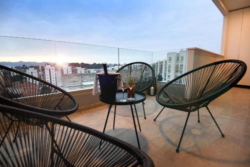 un balcón con 3 sillas y una mesa con una botella de vino en K&P - Zadar Luxurious Retreat - BRAND NEW !! en Zadar