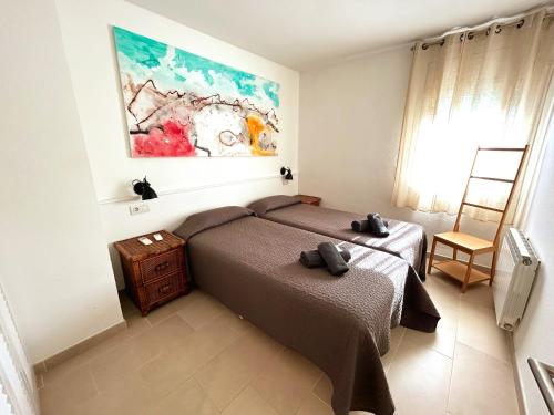 Charming apartment in La Fosca Beach في بالاموس: غرفة نوم بسرير ودهان على الحائط