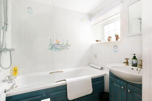 een witte badkamer met een wastafel, een bad en een wastafel bij Woodcutter's Cottage - Peaceful Country Retreat! 