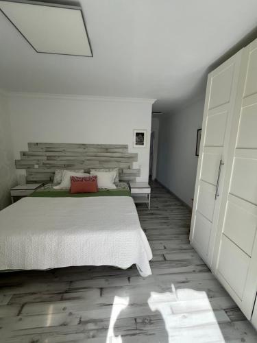 Schlafzimmer mit einem weißen Bett und Holzboden in der Unterkunft SUL MARE in Puerto de Santiago