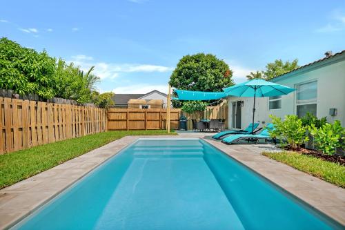 a swimming pool with an umbrella and two blue chairs and an umbrella at 3 Bed 2 Bath w/pool & BBQ next to Keys in Homestead