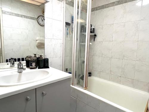 une salle de bain blanche avec un lavabo et une douche dans l'établissement L'appartement Vavin, à Paris