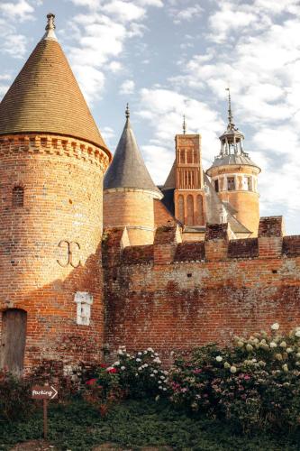 a brick wall with two turrets and some buildings at Château de Tilly in Boissey-le-Châtel