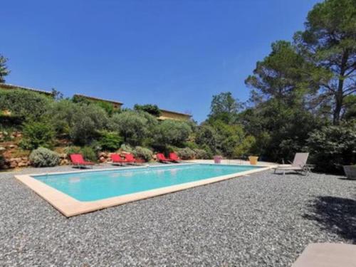 a swimming pool with red chairs and a house at Gîte/Appartement Saint Bernard in Le Thoronet