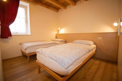 2 camas en una habitación pequeña con ventana en Ciasa Torta, en Moena