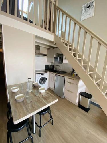 une cuisine avec une table et des chaises ainsi qu'un escalier dans l'établissement Fleur Marine - Bienvenue, à Les Sables-dʼOlonne