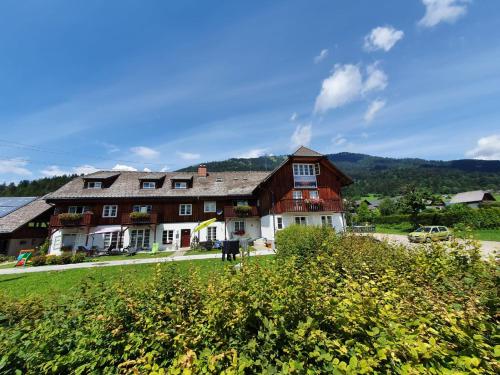 a large wooden house on a green field at Haus Kampl - Appartement Ödensee in Obersdorf