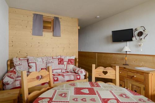 - une chambre avec une table, un lit et une télévision dans l'établissement travelski home select - Vue Pistes, à La Plagne