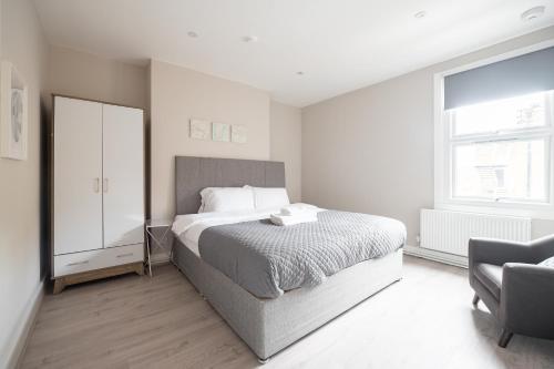 a white bedroom with a bed and a chair at Kennington Apartment D/Apartment in London