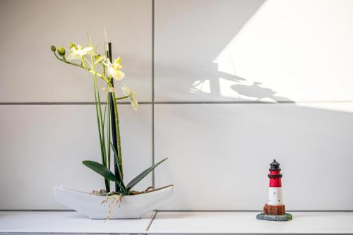 a white vase with a plant and a lighthouse at Haus Heidorn in Sittensen