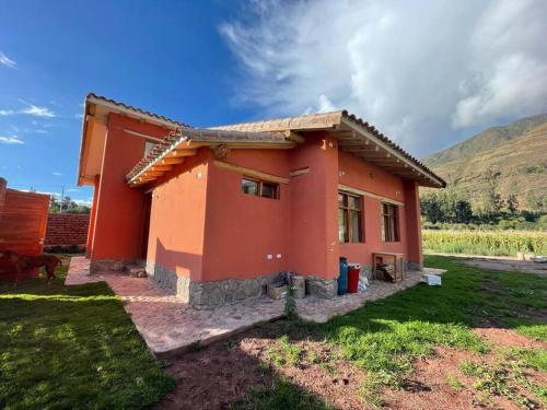 a small red house in a field with a mountain at Cute House Surrounded by Nature in Yucay