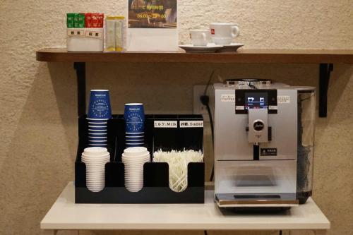 a coffee machine sitting on a shelf with cups at Asta Hotel in Tokyo