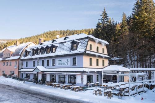 ペツ・ポト・スニェシュコウにあるHotel Krokusの雪の中にテーブルと椅子が置かれた大きな建物