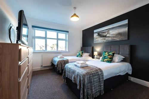 two beds in a room with a tv and a bedroom at Bluebell House in Southampton