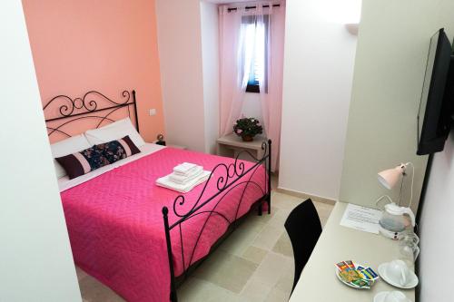 a bedroom with a pink bed and a table at Duomo Guest House in Barletta
