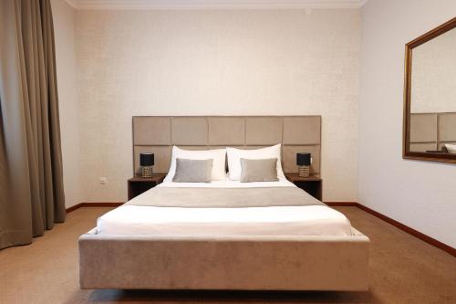 a bedroom with a large white bed with two lamps at Hotel Vidović in Banja Luka