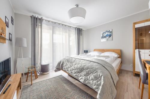 - une chambre blanche avec un lit et une télévision dans l'établissement Apartamenty Sun & Snow Rezydencja Park, à Mielno