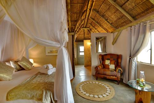 a bedroom with a canopy bed and a chair at Eco-Lodge Gamagara Africa 