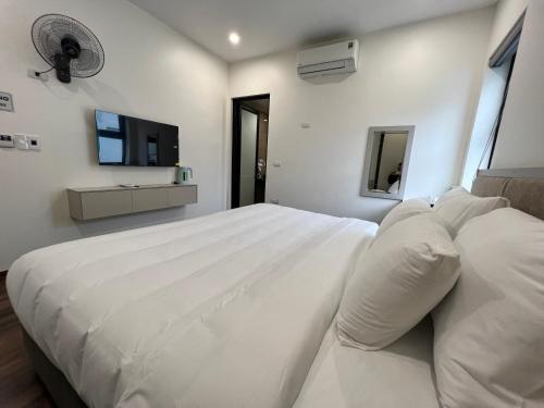 a white bedroom with a large bed and a flat screen tv at Grand Dragon Noi Bai Hotel in Hanoi