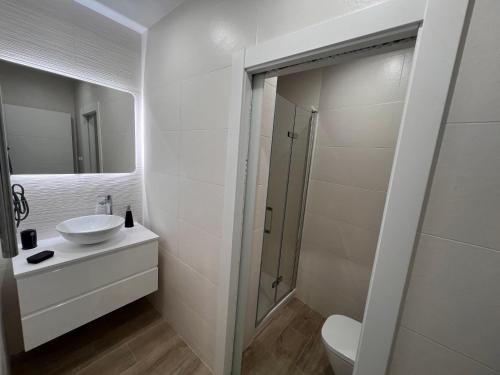 La salle de bains blanche est pourvue d'un lavabo et d'une douche. dans l'établissement LOFT SALAMANCA n 1, à Salamanque