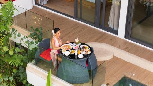 a woman sitting at a table with a plate of food at Three Monkeys Villas in Patong Beach