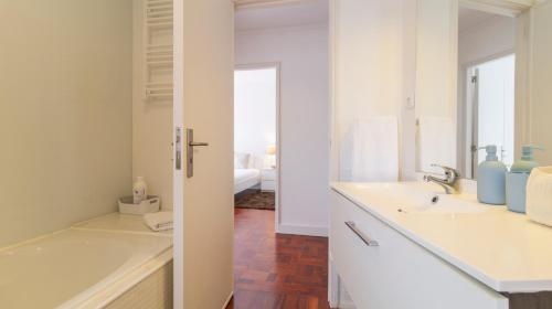Baño blanco con bañera y lavamanos en Fabulous Boavista Apartment by Unique Hosts en Oporto