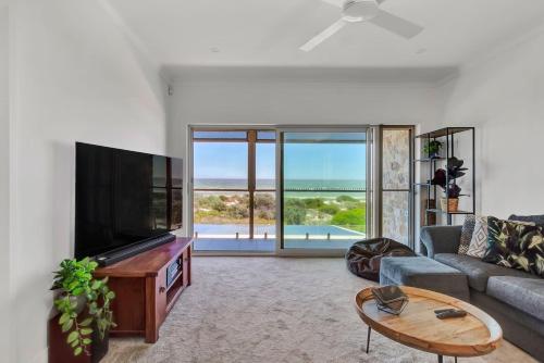 a living room with a tv and a couch and a table at Sandpiper Retreat - Breathtaking Beachfront Panorama in Adelaide