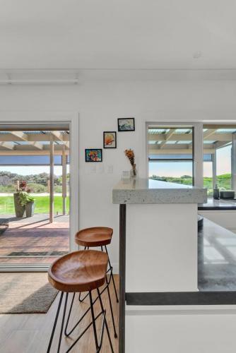 a kitchen with two stools next to a counter at Sandpiper Retreat - Breathtaking Beachfront Panorama in Adelaide