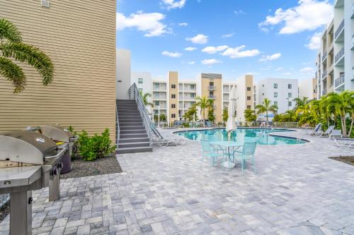 a patio with a pool and chairs and buildings at Waterside Retreat: Modern 2BR, Mins to Beach & Apt in Sarasota