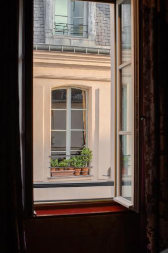 a window with two potted plants on a window sill at Hôtel du Petit Moulin, Haute Couture hotel by Lacroix in Paris