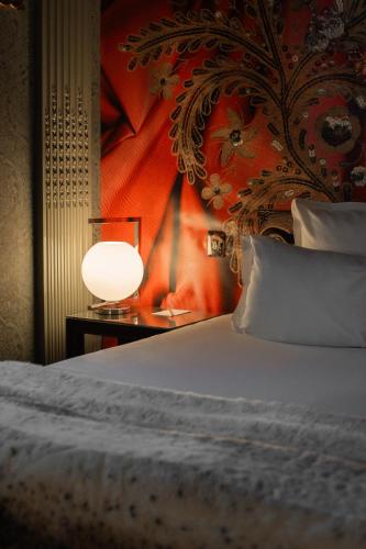 a bedroom with a bed and a lamp on a table at Hôtel du Petit Moulin, Haute Couture hotel by Lacroix in Paris