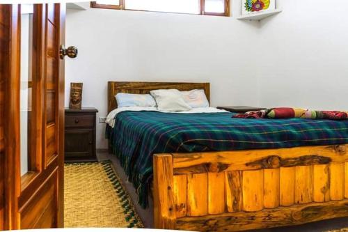 1 dormitorio con cama de madera y manta verde en La casa del colobri, en Cotacachi