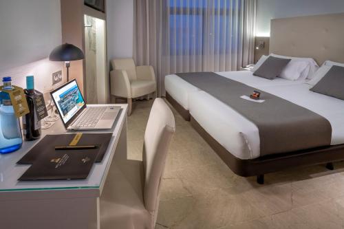 Habitación de hotel con cama y escritorio con ordenador portátil en Hotel SERHS Del Port en Barcelona