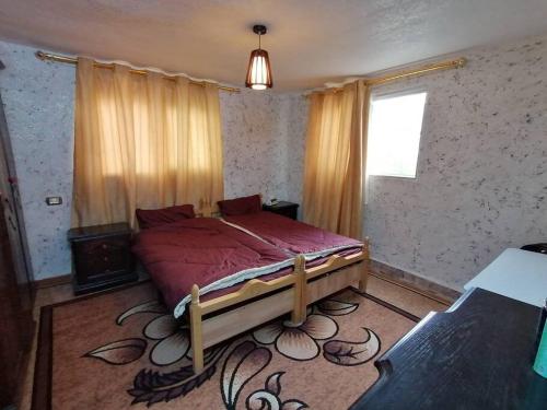 una camera da letto con un letto con lenzuola rosse e una finestra di Rural house البيت الريفي a Ajloun