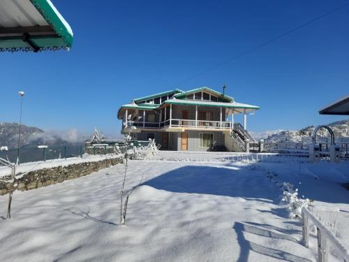 a house on top of a snowy hill with a building at HighField Villa in Kanatal